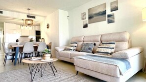 Ett vardagsrum med en soffa, ett soffbord och en matplats med stolar.