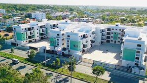 A modern residential complex with multiple buildings, a central courtyard, and a road in the foreground. - Apartment 10 minutes from Las Americas International Airport and the beach. (Santo Domingo Este)