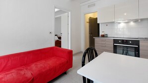 Une cuisine moderne avec des meubles blancs, un canapé rouge et une table à manger.