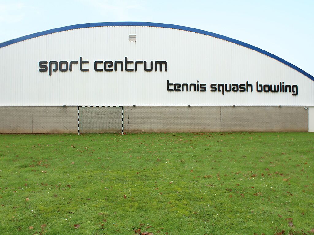 Ein großes, weißes Gebäude mit Schildern für ‚sport center‘, Tennis, Squash und Bowling.