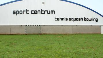 Ein großes, weißes Gebäude mit Schildern für ‚sport center‘, Tennis, Squash und Bowling.
