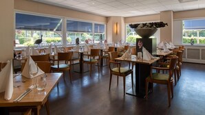 A restaurant with multiple tables and chairs, large windows, and a central decorative feature. - A Place You'll Surely Enjoy! Indoor Pool, Near Henriette Polak Museum! (Zutphen)