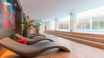 Un espace spa moderne doté de fauteuils inclinables, d’une grande fenêtre et d’une vue sur la piscine.