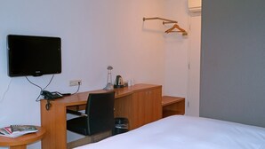 Une chambre d’hôtel comprenant un lit, un bureau avec une chaise, une télévision et un porte-manteau.
