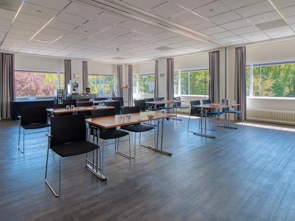 Een vergaderzaal met een lange tafel, stoelen en grote ramen.