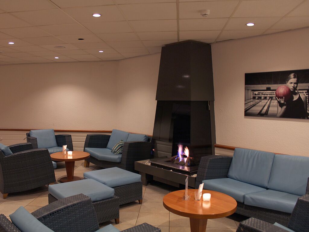 A lounge area with sofas, a fireplace, and a bowling-themed wall art.