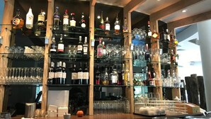 Eine Bar mit mehreren Regalen voller Spirituosenflaschen und Gläsern.