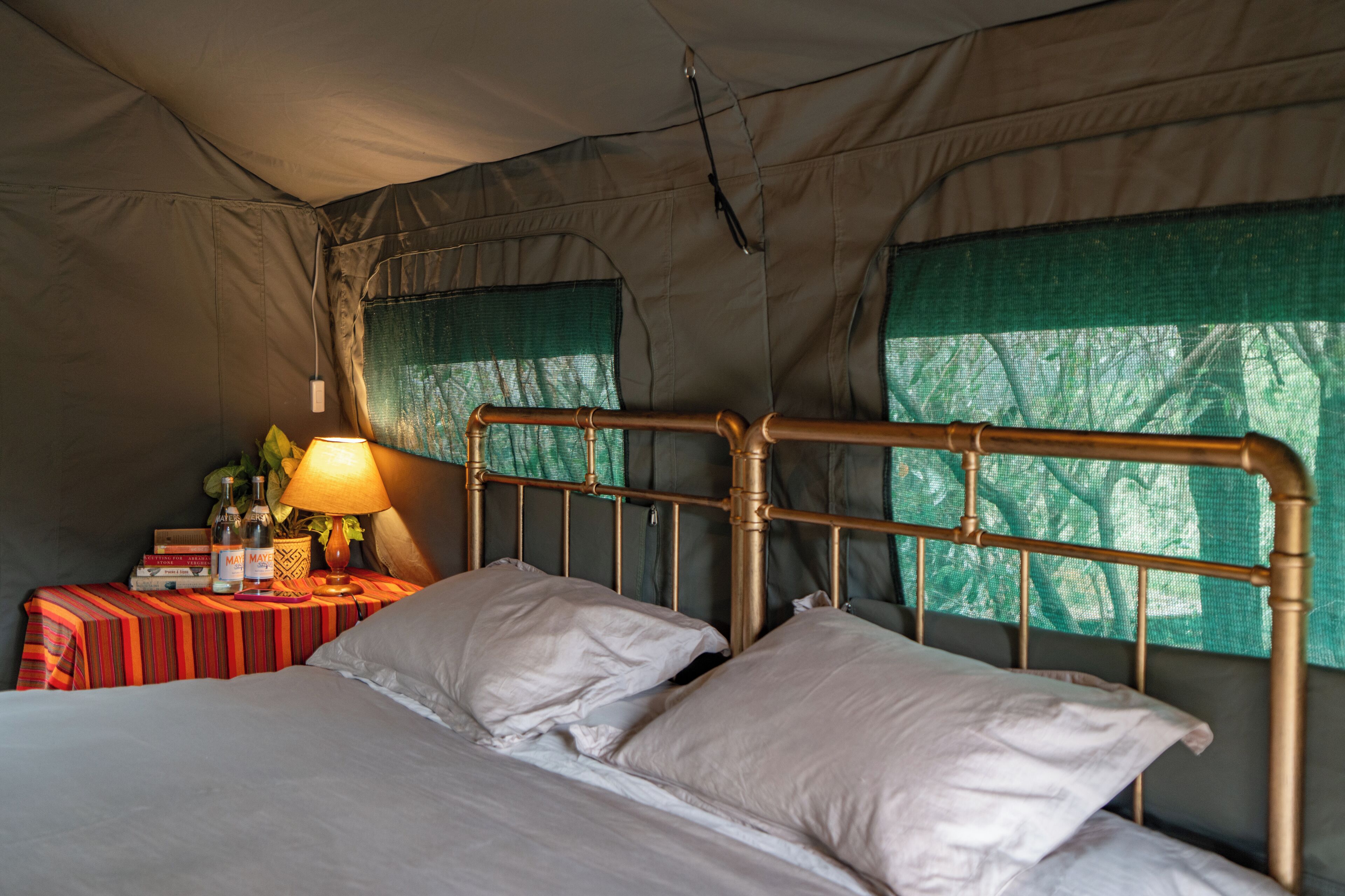 A tented room with a bed, a nightstand, and a lamp.