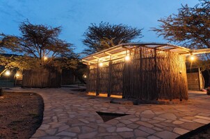 Un espacio al aire libre con pavimento de piedra, una estructura de paja e iluminación con luces colgantes.