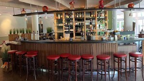 Un espace bar avec des tabourets, des étagères remplies de bouteilles et un comptoir.