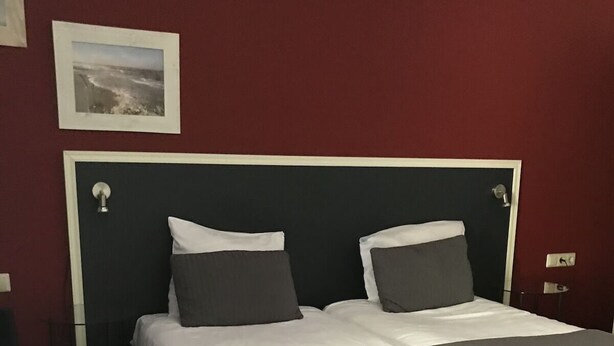 Een standaard hotelkamer met een bed, nachtkastjes en een aan de muur hangend schilderij.