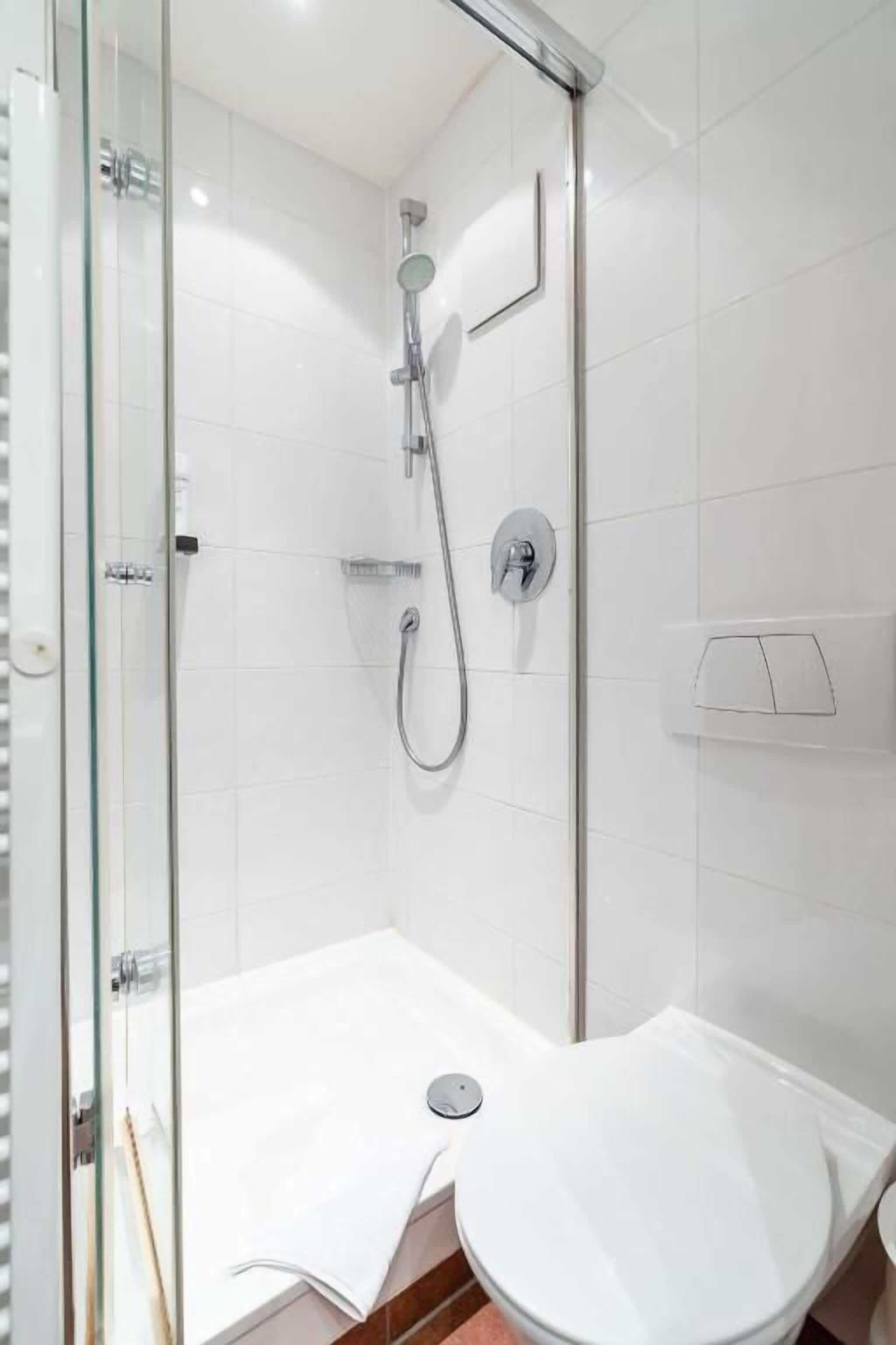 Une salle de bain moderne avec une douche à parois de verre, des toilettes blanches et un lavabo.