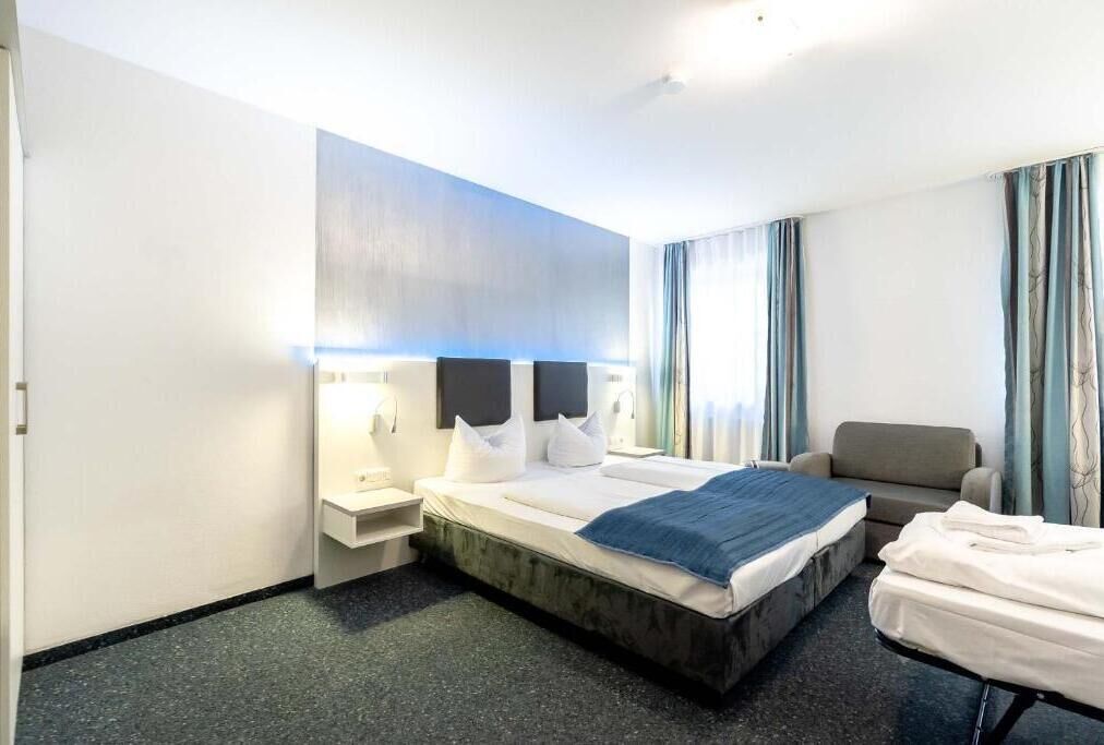 A hotel room with a bed, bedside tables, a chair, and a desk.