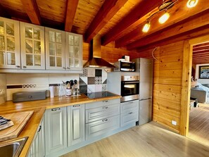 A kitchen with wooden beams, a microwave, oven, and a sink. - Stunning Alpine chalet for seven people with breathtaking mountain views! (La Chapelle-d'Abondance)