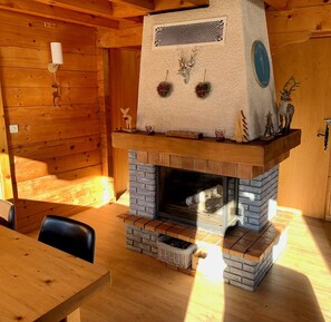 Un intérieur de chalet chaleureux avec une cheminée, des murs en bois et un coin repas.