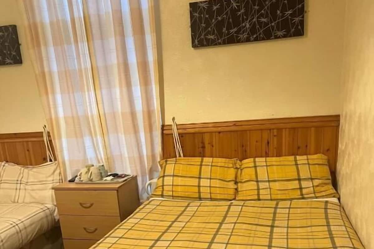 Een hotelkamer met een bed, nachtkastje, dressoir en een kunstwerk aan de muur.