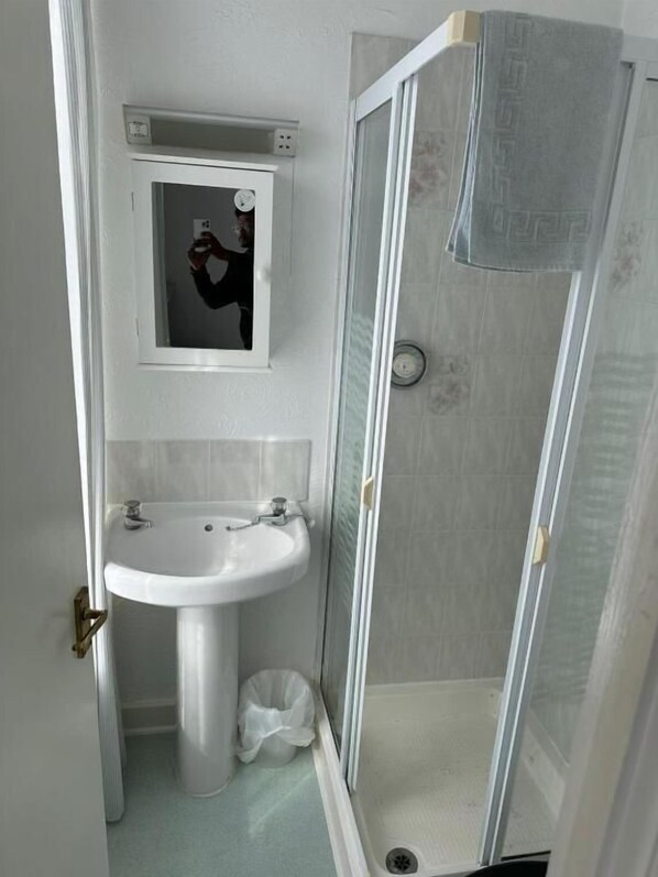 A bathroom with a pedestal sink, a mirror, and a glass-enclosed shower. - The stage door hotel (Blackpool)