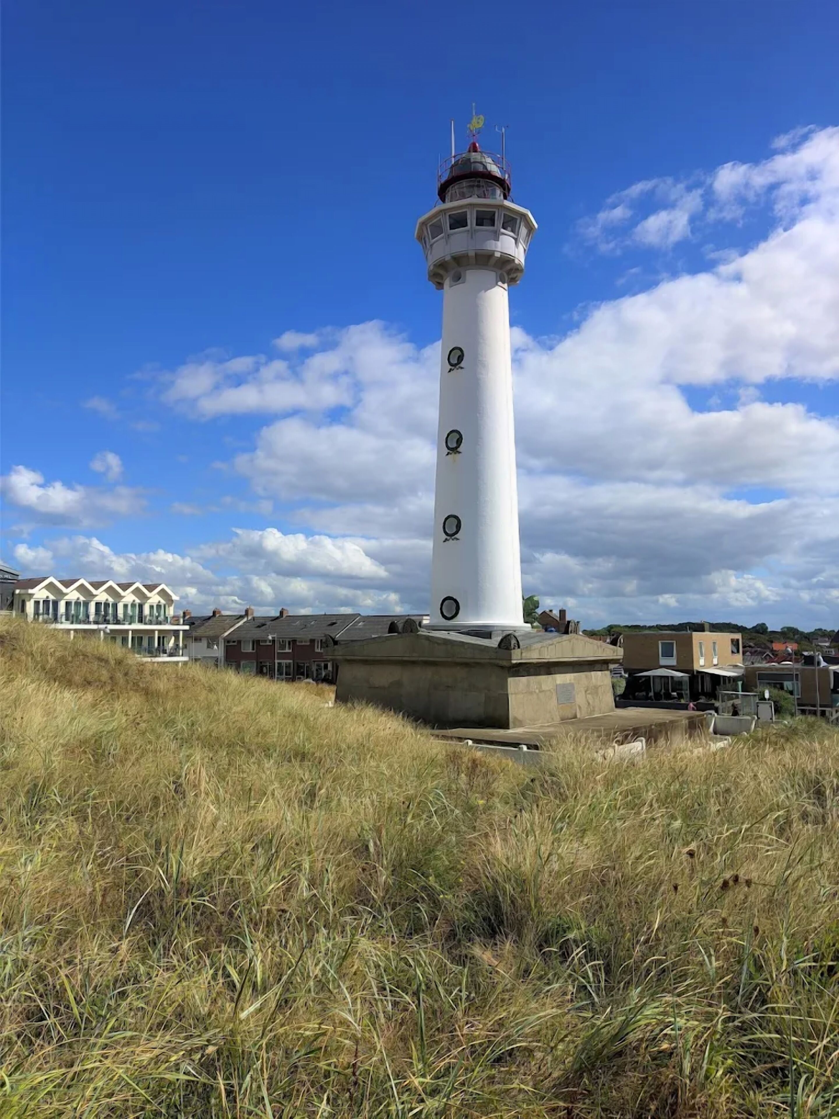 Un faro con una torre cilíndrica, una base circular y una veleta en la parte superior.
