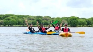 A group of people kayaking on a calm river with trees in the background. - Easy Nest Residency (Kannur)
