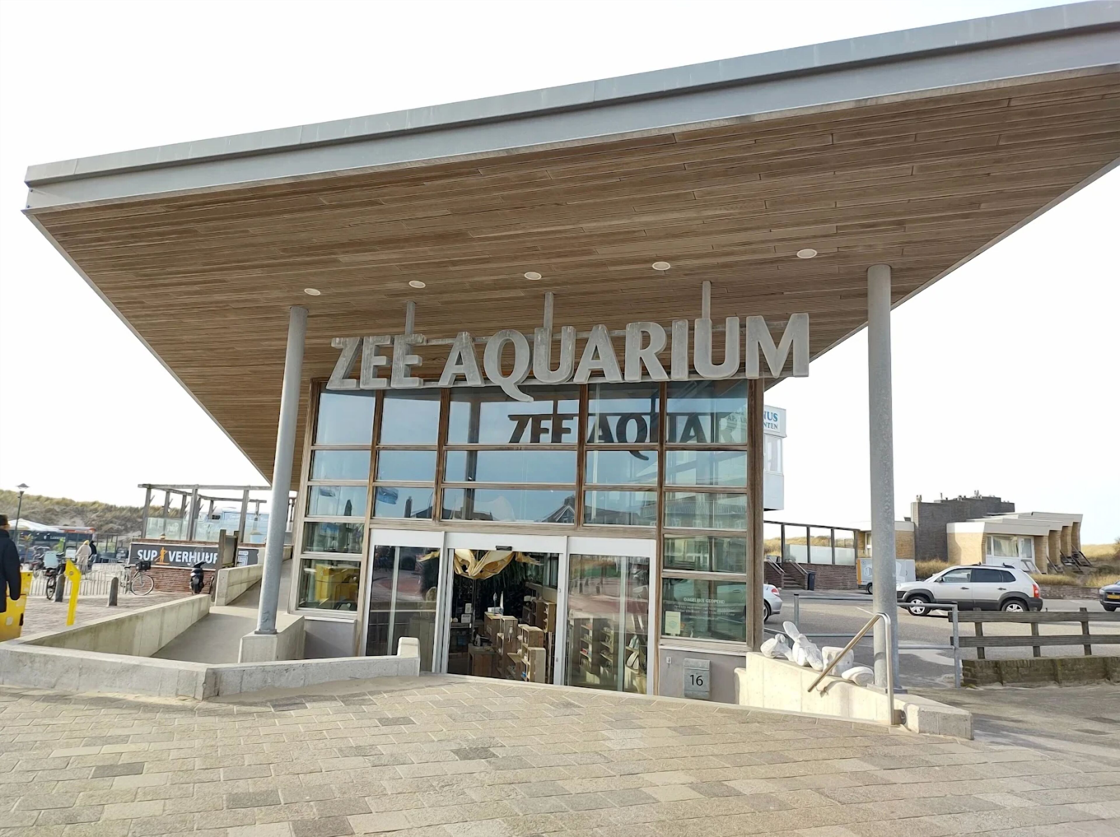 Het uiterlijk van ZEE AQUARIUM, met een modern ontwerp, met een grote glazen gevel en een houten overkapping.