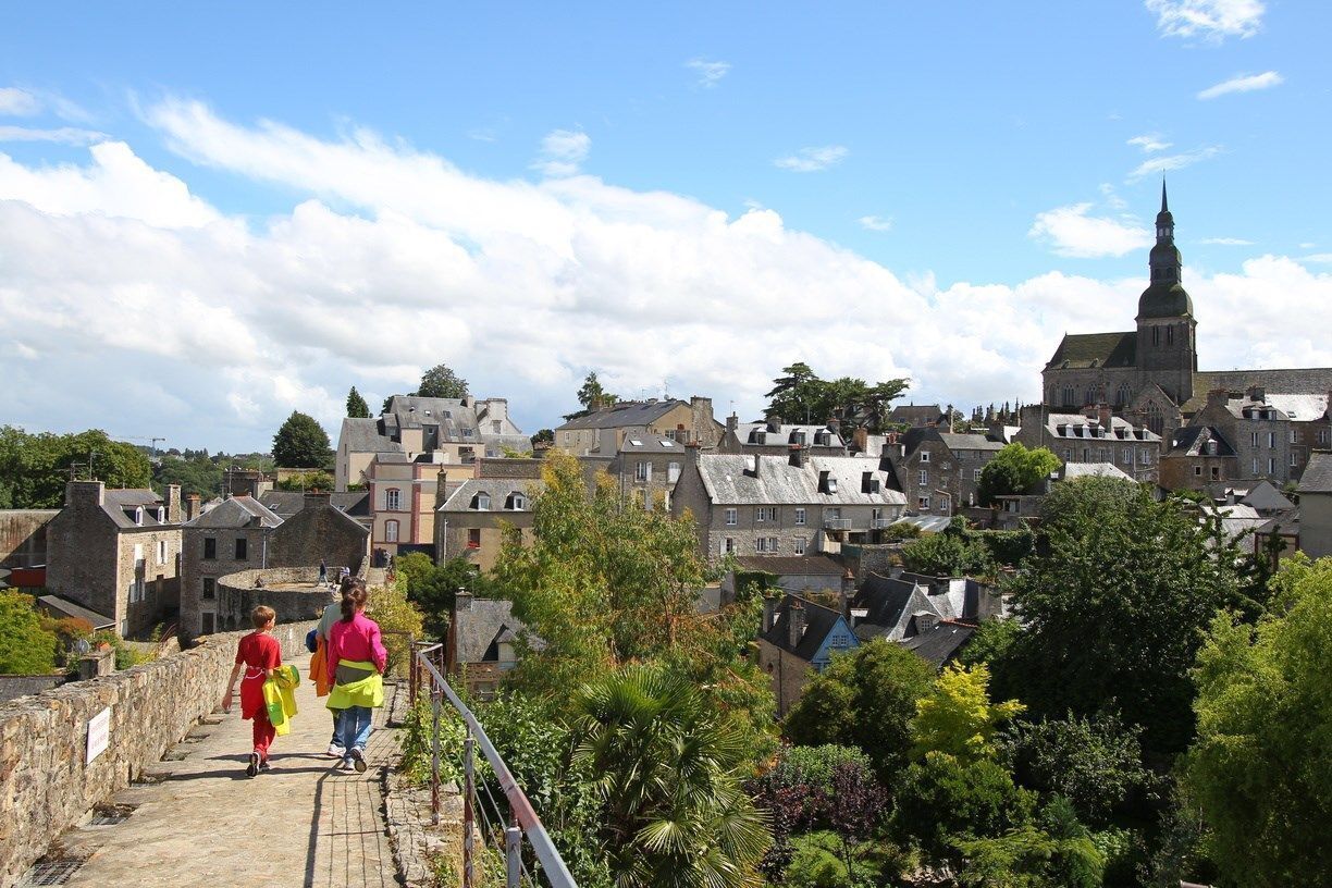 A stone pathway leading to a town with historic buildings and a prominent church spire.