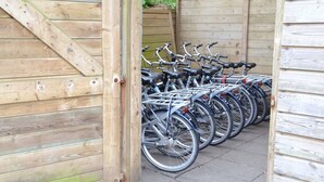 Een rij fietsen geparkeerd voor een houten gebouw met een schuin dak.