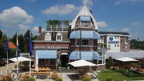 Een hotel met een geruit luifel, terraszitplaatsen en een tuintje.