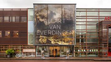Een gebouw met een groot reclamebord waarop 'Allart Van Everdingen' en 'Het Ruige Landschap' staan.
