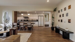 A modern kitchen with white cabinets, a dining area with wooden chairs, and a living room with a sofa and coffee table. - 5 mins walk to Jing'an temple, 4br, 2bth, Family friendly! (Shang Hai Shi)