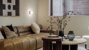 A modern living room with a leather sofa, a round coffee table, and a vase with branches. - 5 mins walk to Jing'an temple, 4br, 2bth, Family friendly! (Shang Hai Shi)