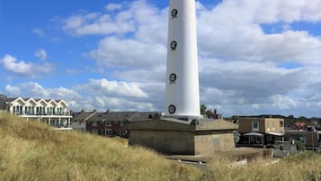 Un faro con una torre cilindrica, una base circolare e una banderuola sulla sommità.