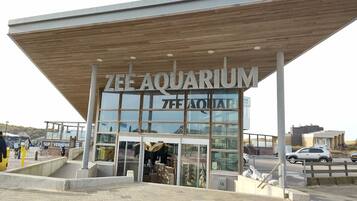 The exterior of ZEE AQUARIUM with a modern design, featuring a large glass facade and a wooden canopy.