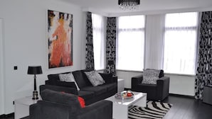Una sala de estar moderna con un sofá, un sillón, una mesa de centro y un tapete con estampado de cebra.
