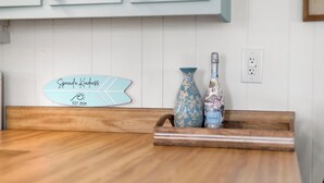 A wooden kitchen counter with a decorative sign, a vase, and a bottle. - Spread'N Kindness | Pet-Friendly + One Block from the Beach (Surf City)