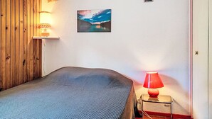 Een kamer met een bed, een wandlamp, een schilderij en een deur.