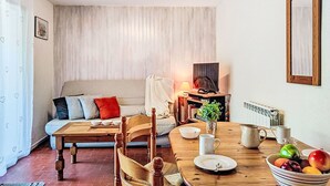 Een gezellige woonkamer met een bank, een houten eettafel en een televisie.