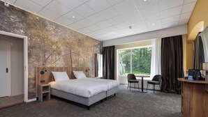 Una habitación de hotel con una cama, un escritorio, una silla y un ventanal grande.