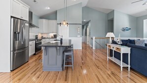 Een moderne keuken met roestvrijstalen apparatuur, een centraal kookeiland en een zithoek met een donkerblauwe bank.