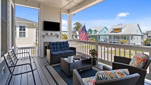 Een overdekte veranda met tuinmeubilair, een flatscreen televisie en een Amerikaanse vlag.