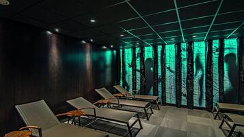 A room with a checkered floor, dark walls, and a row of lounge chairs.