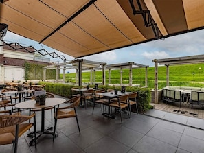 An outdoor patio with tables and chairs, a covered area, and a view of a green field. - Perfect Getaway in Spacious Unit | Nearby Beach & Nature trails | Free Parking (Kamperland)