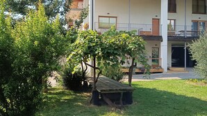 A building with a balcony, a grassy yard, and a wooden bench. - WEEKEND HEALTH WELLNESS REGENERATE (Bossico)