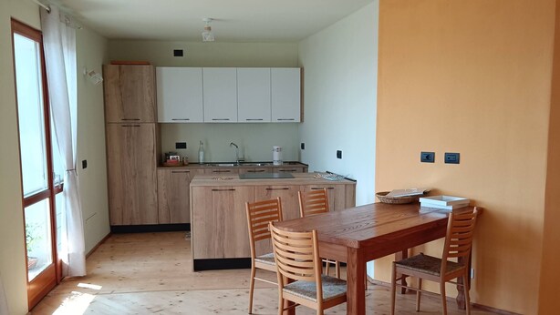 A modern kitchen with white cabinets, a wooden dining table, and a ceiling fan. - WEEKEND HEALTH WELLNESS REGENERATE (Bossico)