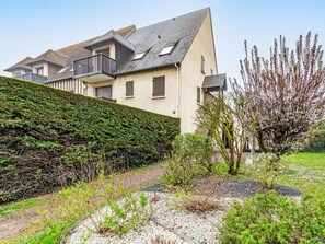 A modern house with a sloped roof, a balcony, and a well-maintained garden with gravel paths and various plants. - Les Sylvestres by Interhome (Cabourg)