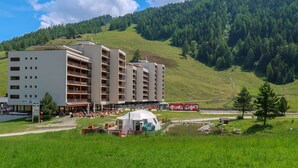 Um hotel com vários andares, área de estar externa e vista para uma paisagem montanhosa.