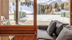 Quarto com uma grande janela que oferece vista para uma paisagem nevada de montanhas.