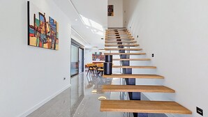 En modern inredning med en trappa, ett matområde och konstverk på väggarna.