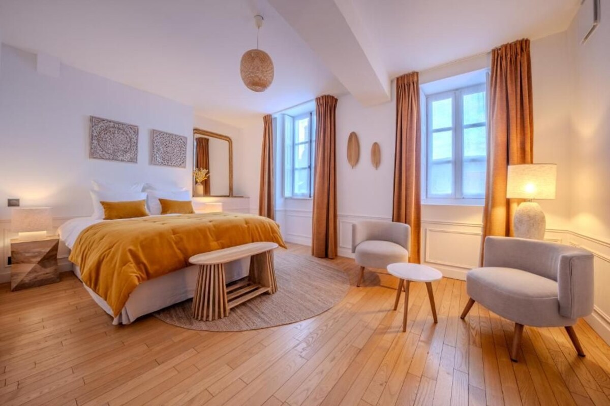 A modern bedroom with a bed, bedside tables, a bench, a chair, and a lamp.