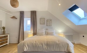A bedroom with a large bed, a skylight, a radiator, and a dresser. - La Salamandre (Orléans)