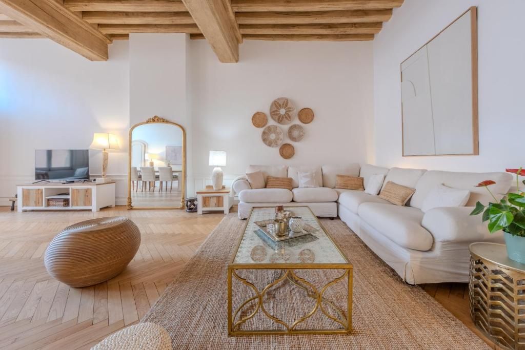 A modern living room with a white sofa, a coffee table, a large mirror, and decorative wall art.